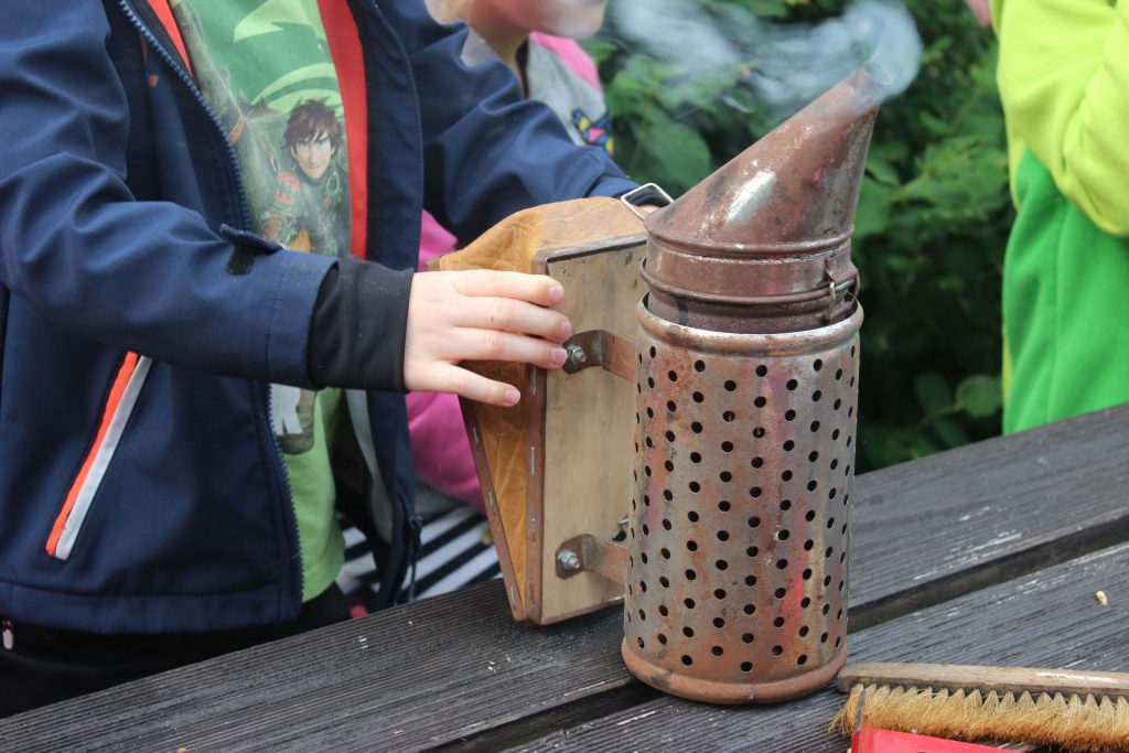 Hier dürfen die Kinder auch selbst mal ausprobieren. Mit der Imkerpfeife werden die Bienen beruhigt.